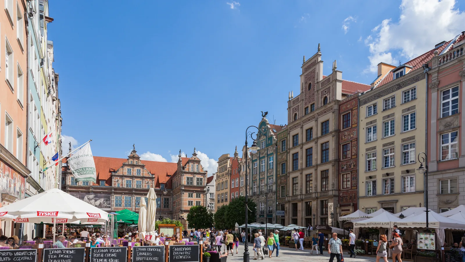Długi Targ w Gdańsku: kamienice, ogródki restauracji z parasolami i turyści w słoneczny dzień